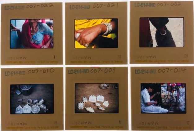 Slides. Four colour slides show close ups of an ear with rings hanging over the upper helix, silver cuff bracelets on dark-skinned arms, the lower legs and shoes of a person standing next to a bicycle, and a red turban catching light in an otherwise shadowy picture.
